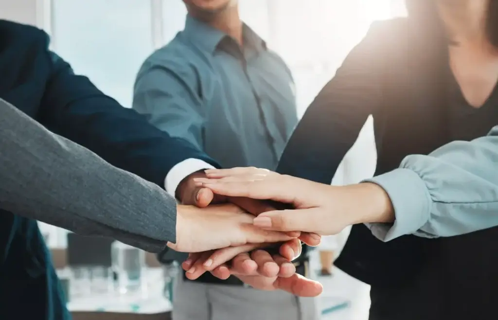 Team der lægger hænderne sammen – symbol på samarbejde, tillid og fælles værdier hos Flexum Coworking